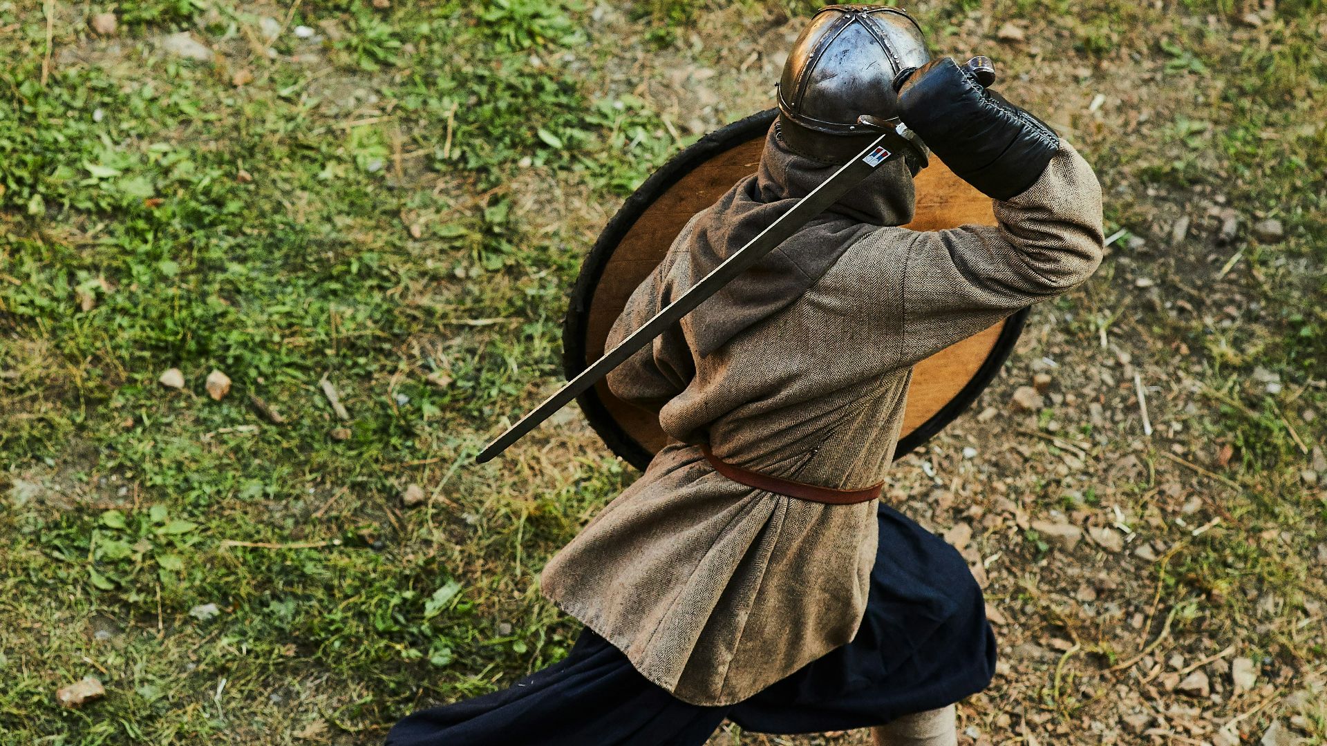 boy in brown jacket and blue pants holding black bow