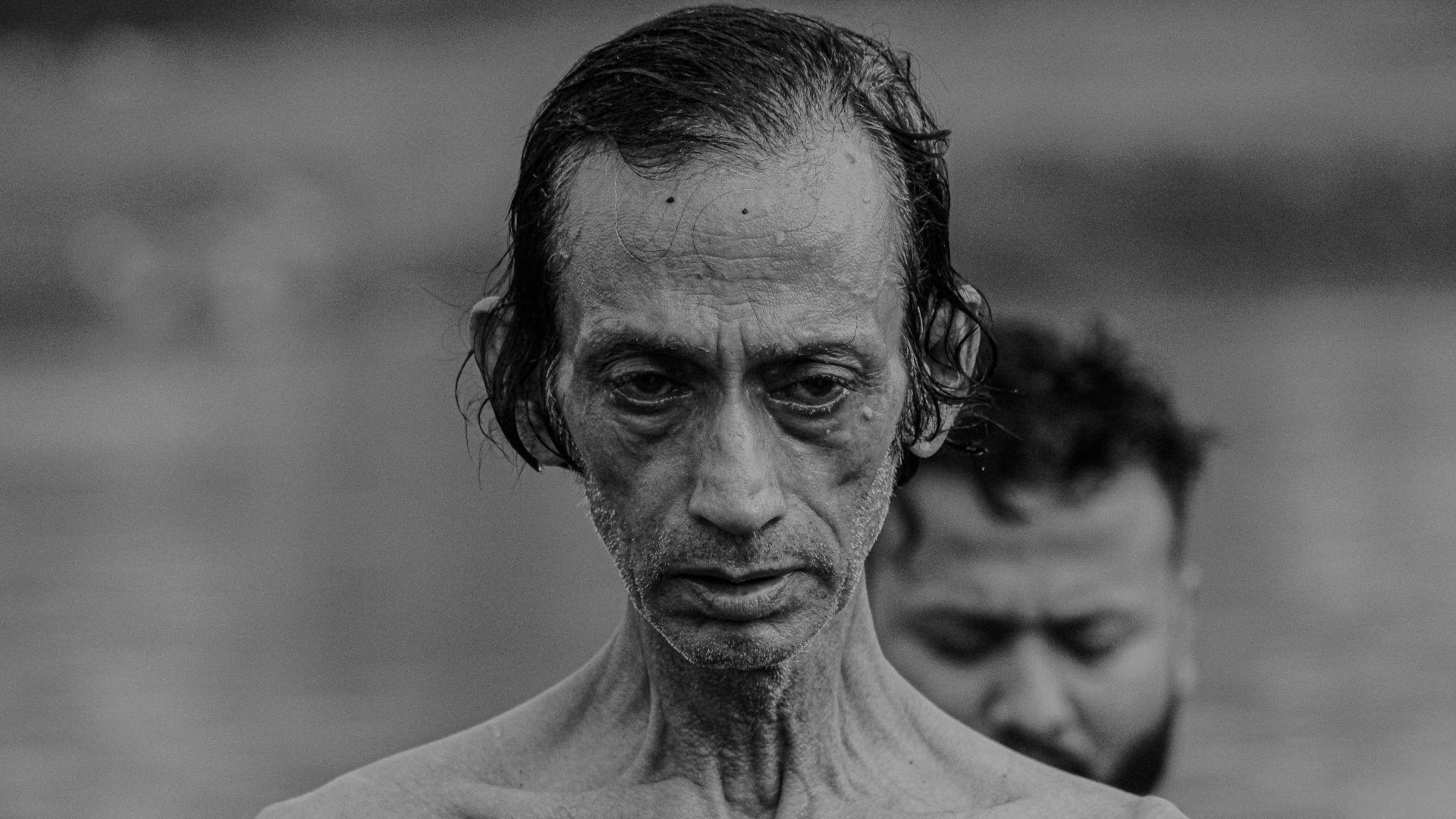 a man with no shirt standing next to another man