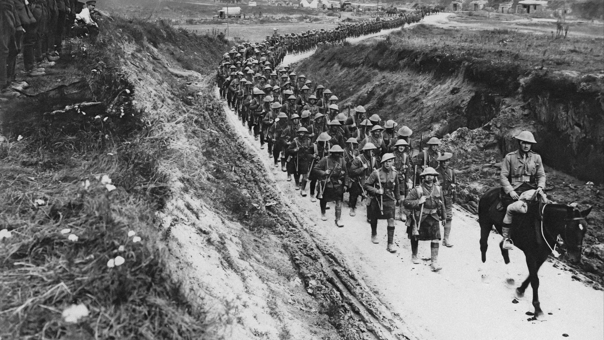a group of men riding horses down a dirt road