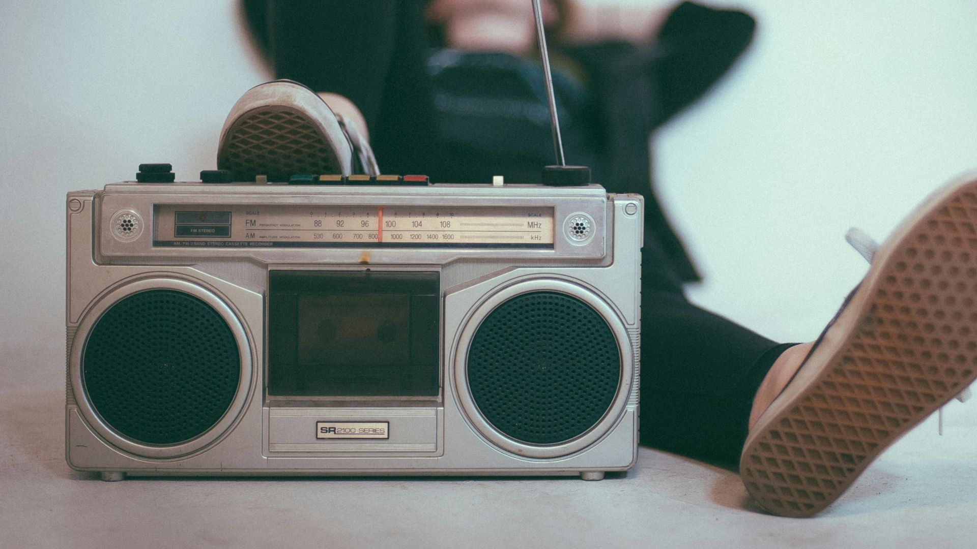 woman laying on bed near gray radio