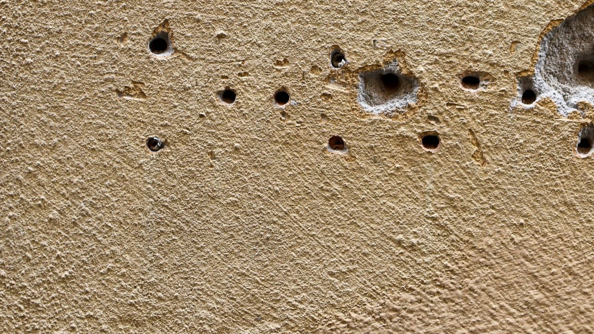 A wall displays holes from impact damage.