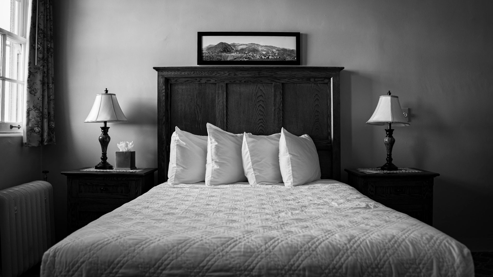 A black and white photo of a bed in a bedroom
