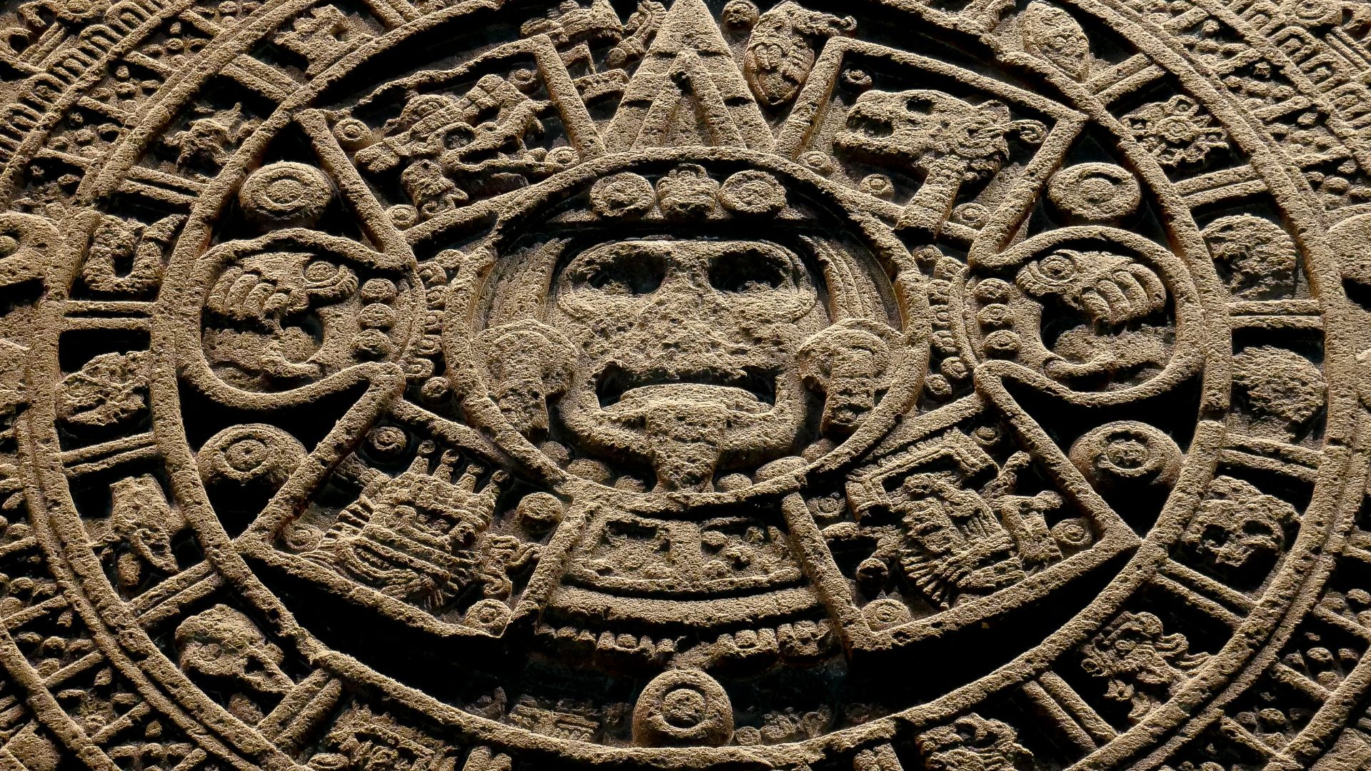 A stone carving of a face with many symbols on it