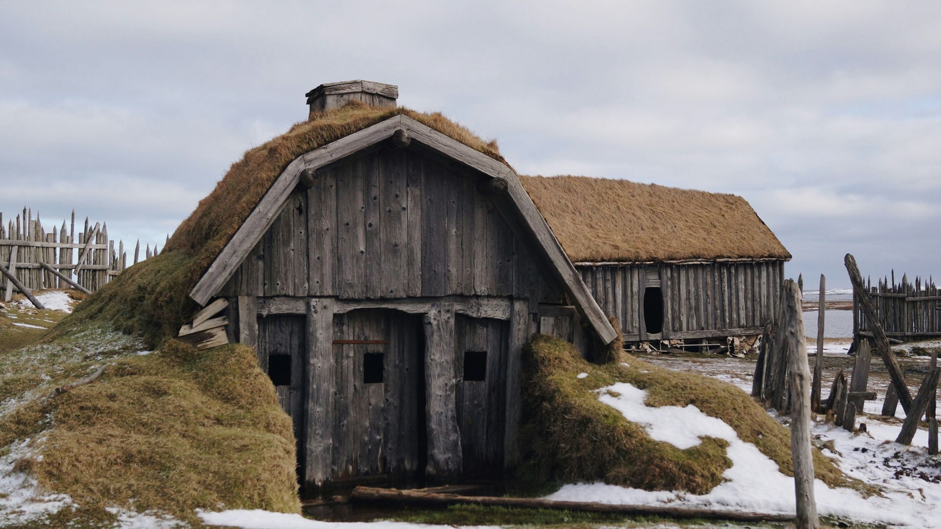 gray wooden house near sea under white skies