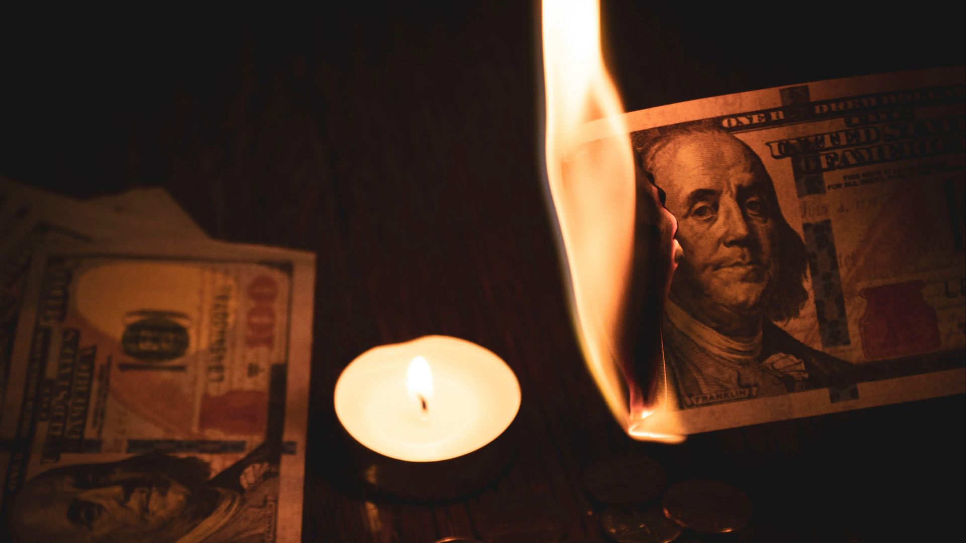 white pillar candle beside 100 us dollar bill
