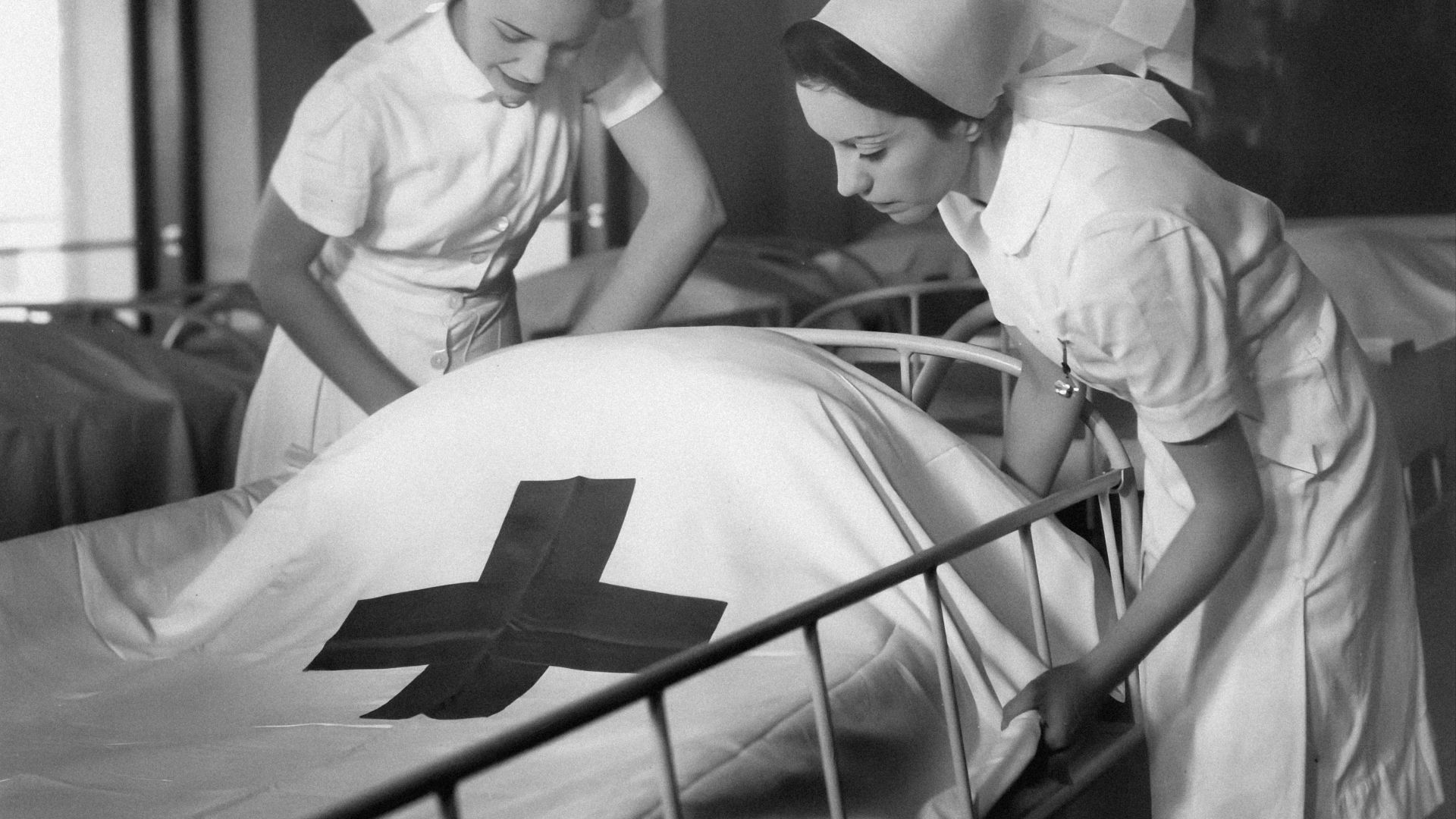 a couple of nurses standing over a bed