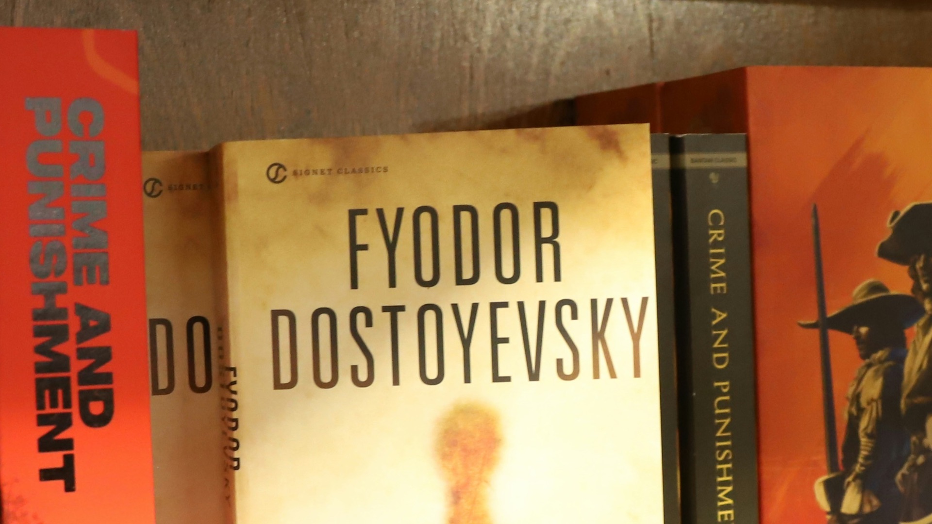 Books on a wooden shelf, including dostoyevsky's the idiot.