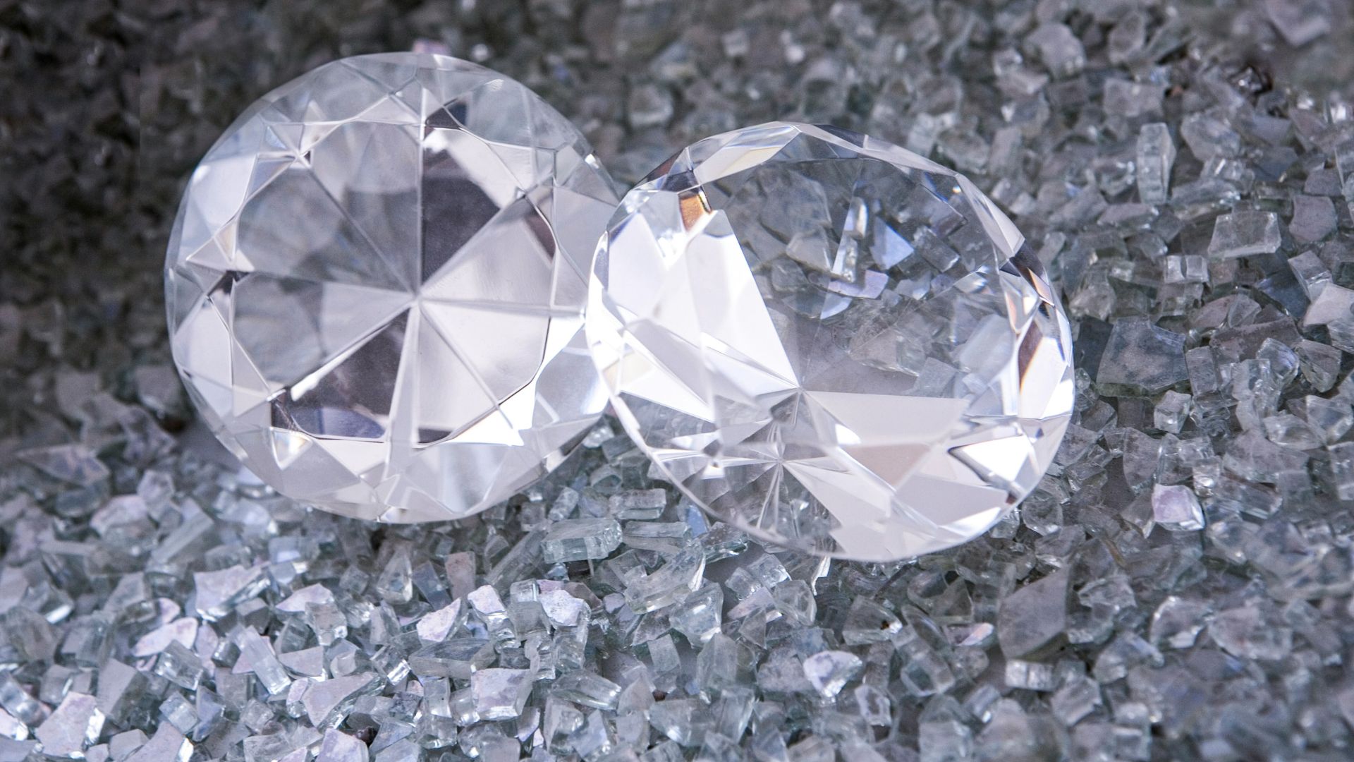 two diamonds sitting on top of a pile of crushed glass