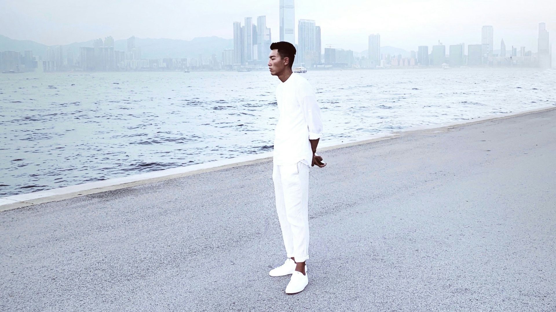 woman in white long sleeve shirt and white pants standing on gray concrete road during daytime