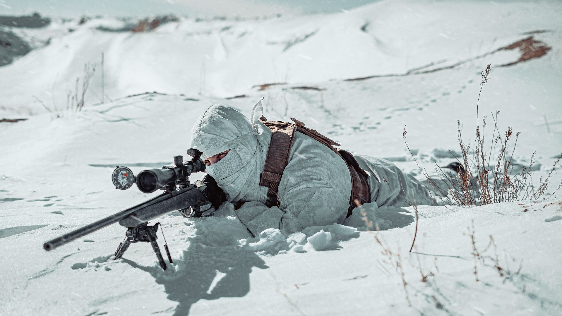 a man laying in the snow with a rifle