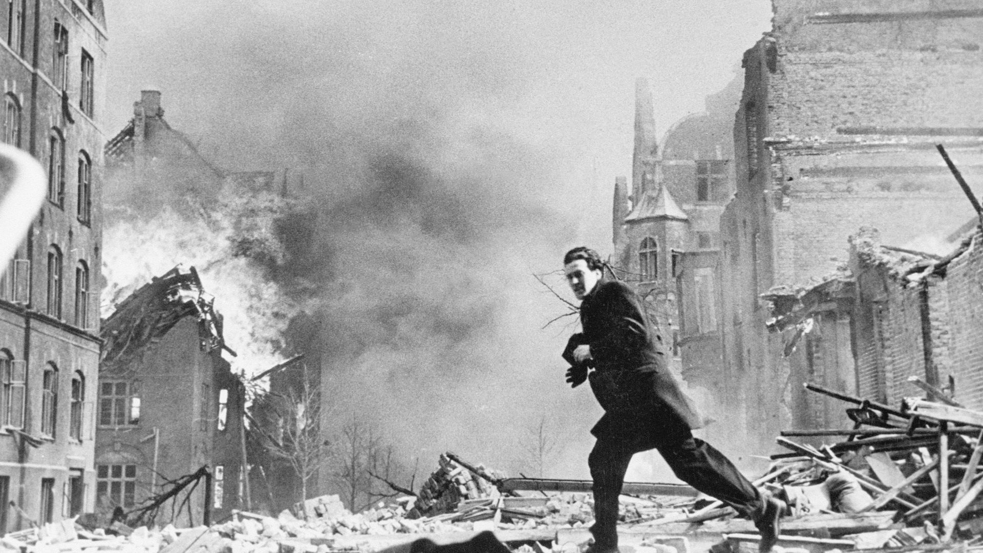 a man walking through a destroyed city street