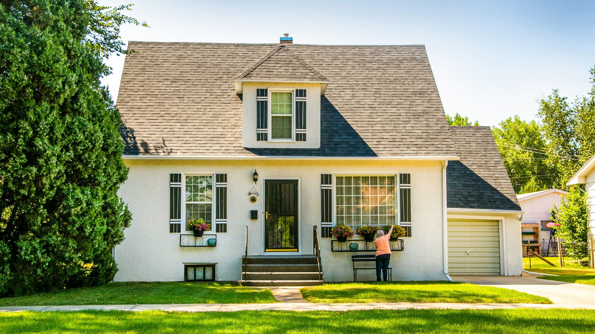 man in black shirt sitting on chair near white wooden house during daytime