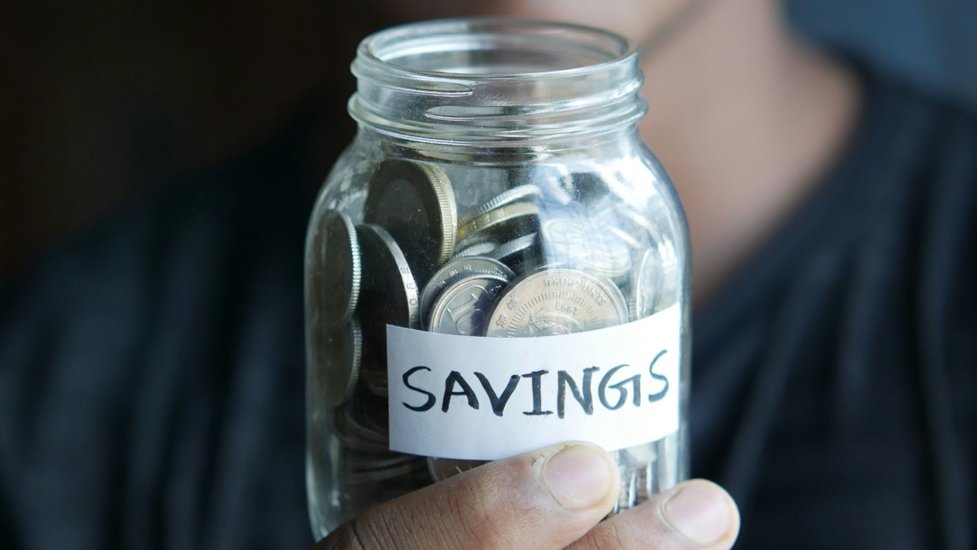 a man holding a jar with a savings label on it
