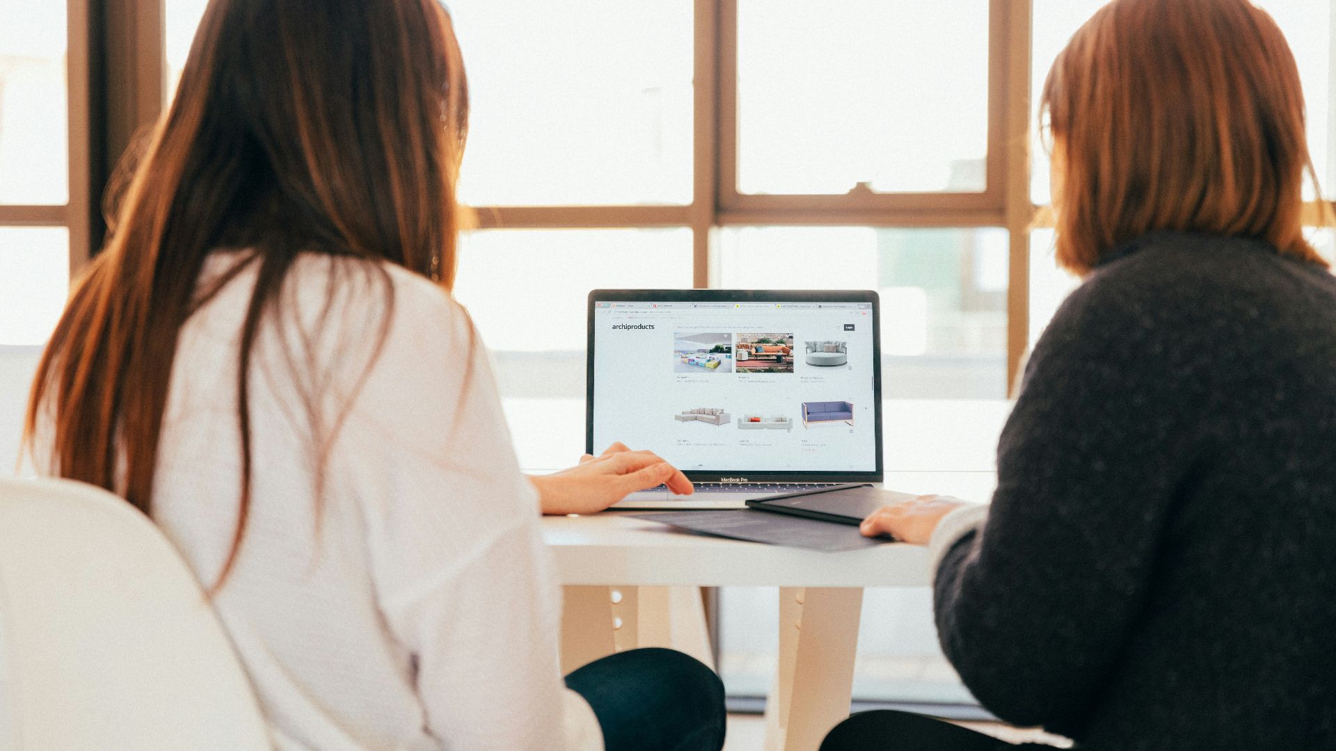 two women talking while looking at laptop computer