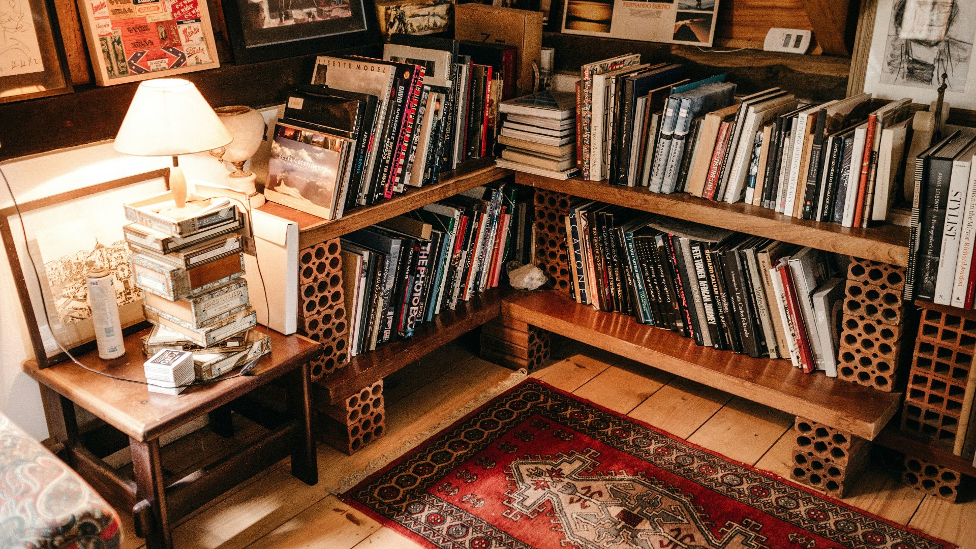 assorted books in shelf near lighted table lamp