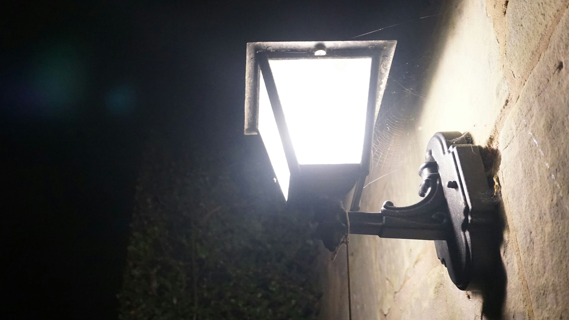 A bright security light illuminates a wall at night.