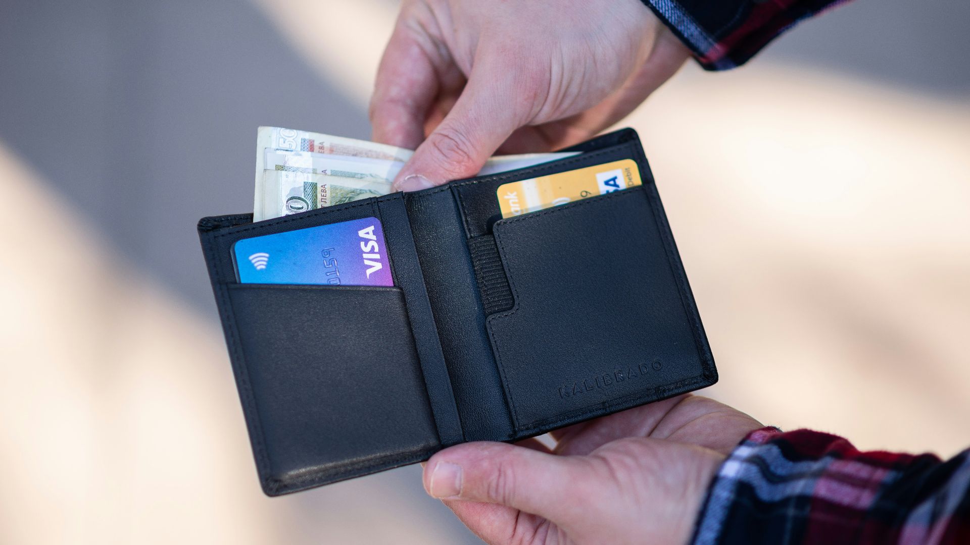 black leather bifold wallet on persons hand