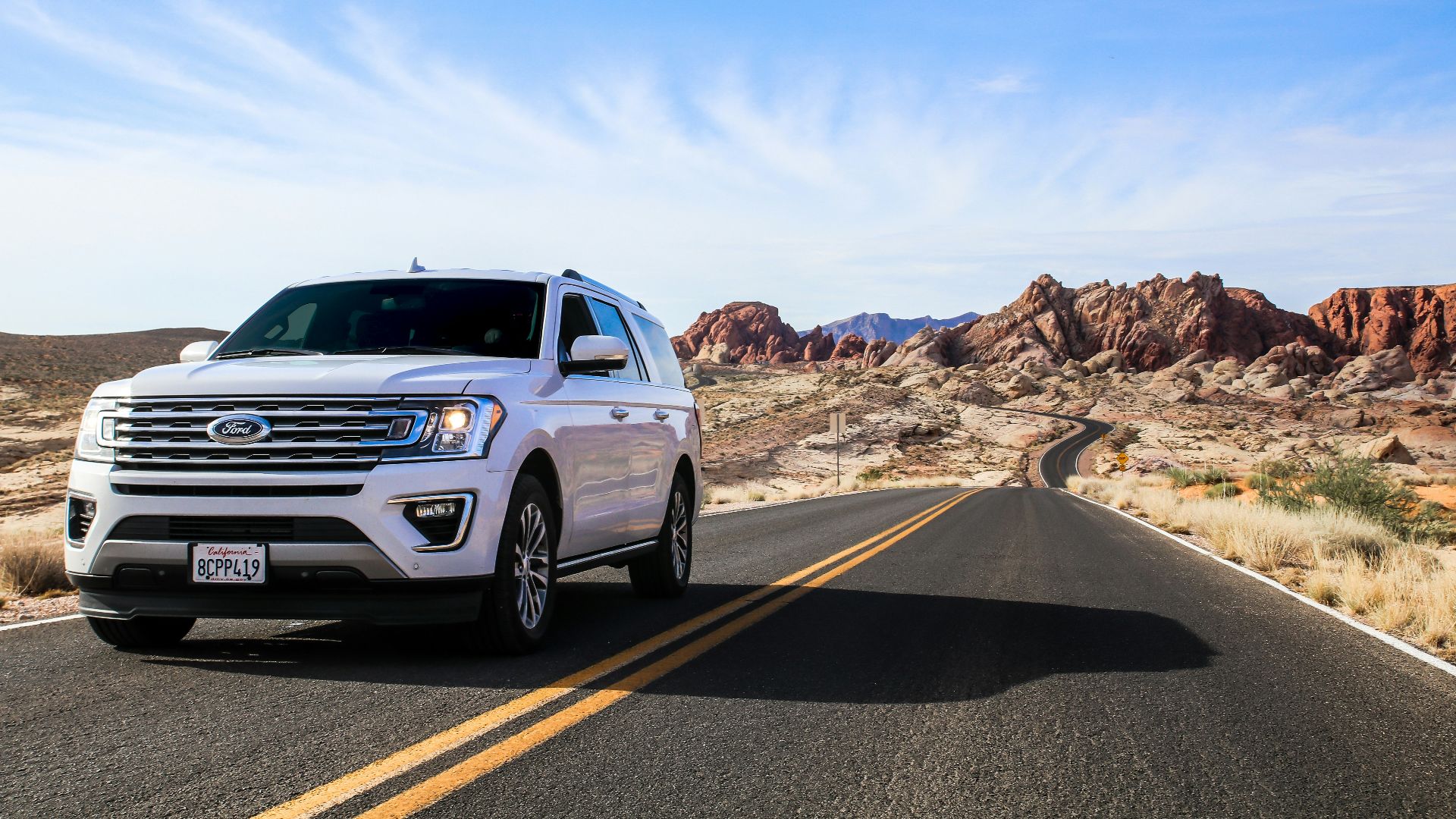 a white suv driving down a desert road