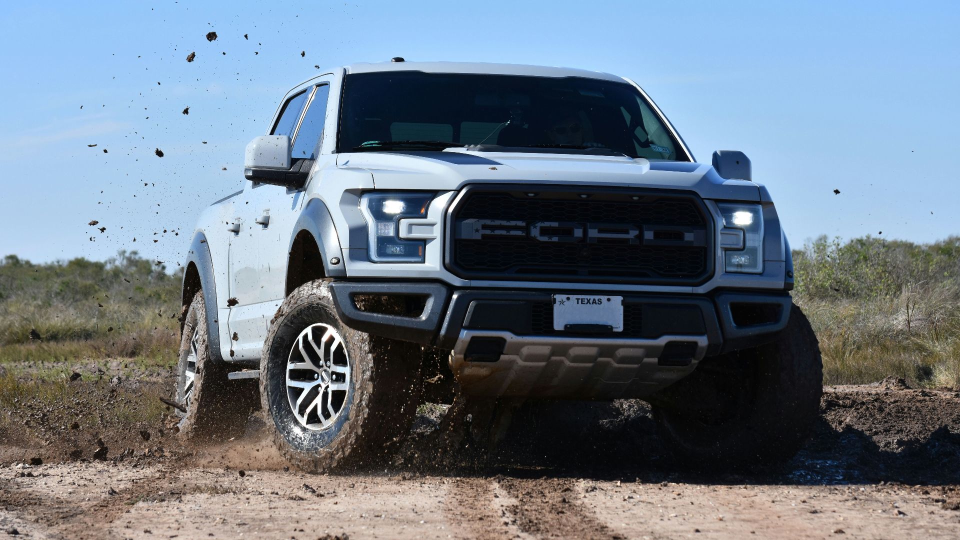 a white truck is driving through the mud