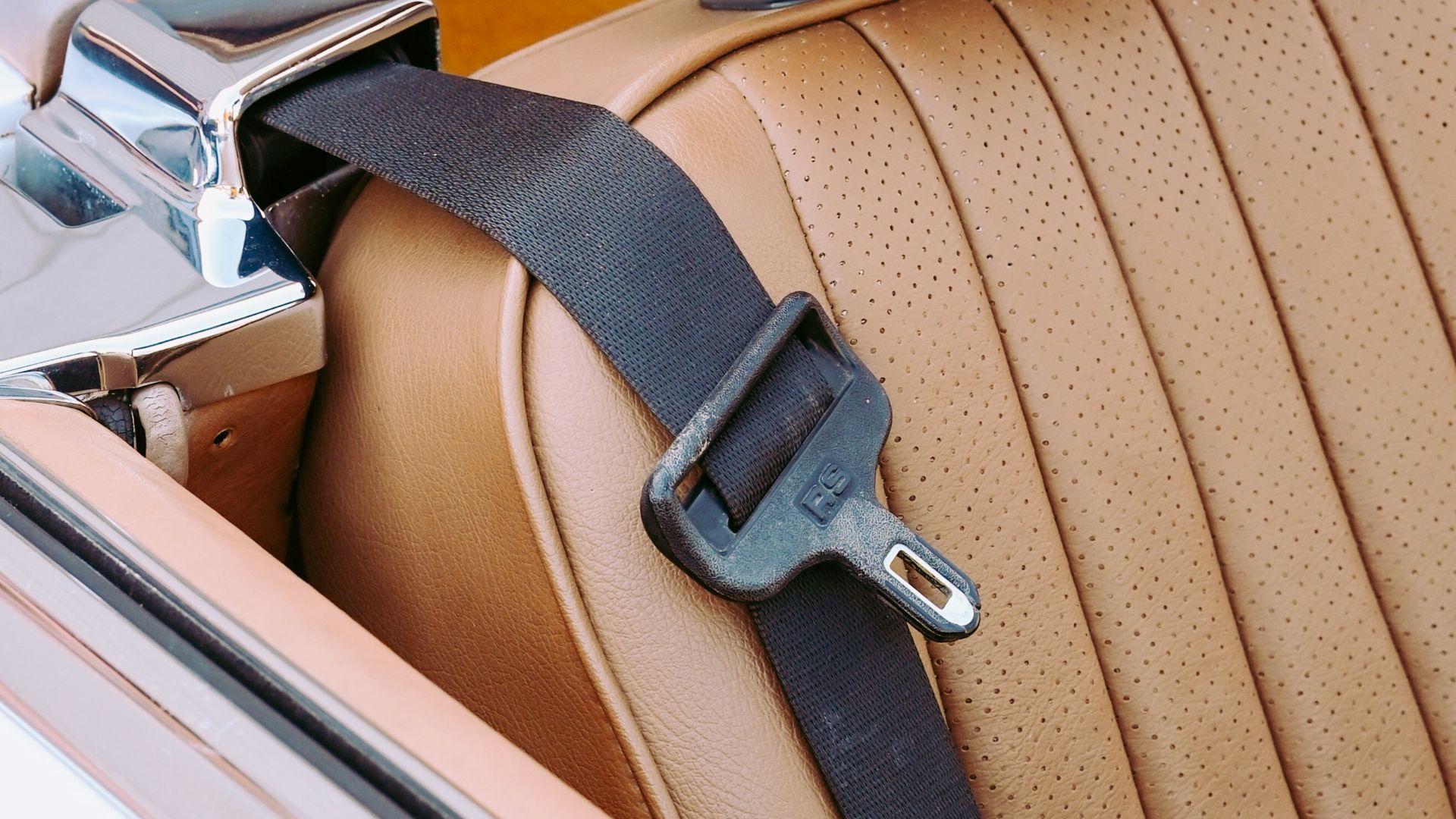A classic car seat with headrest and seatbelt.