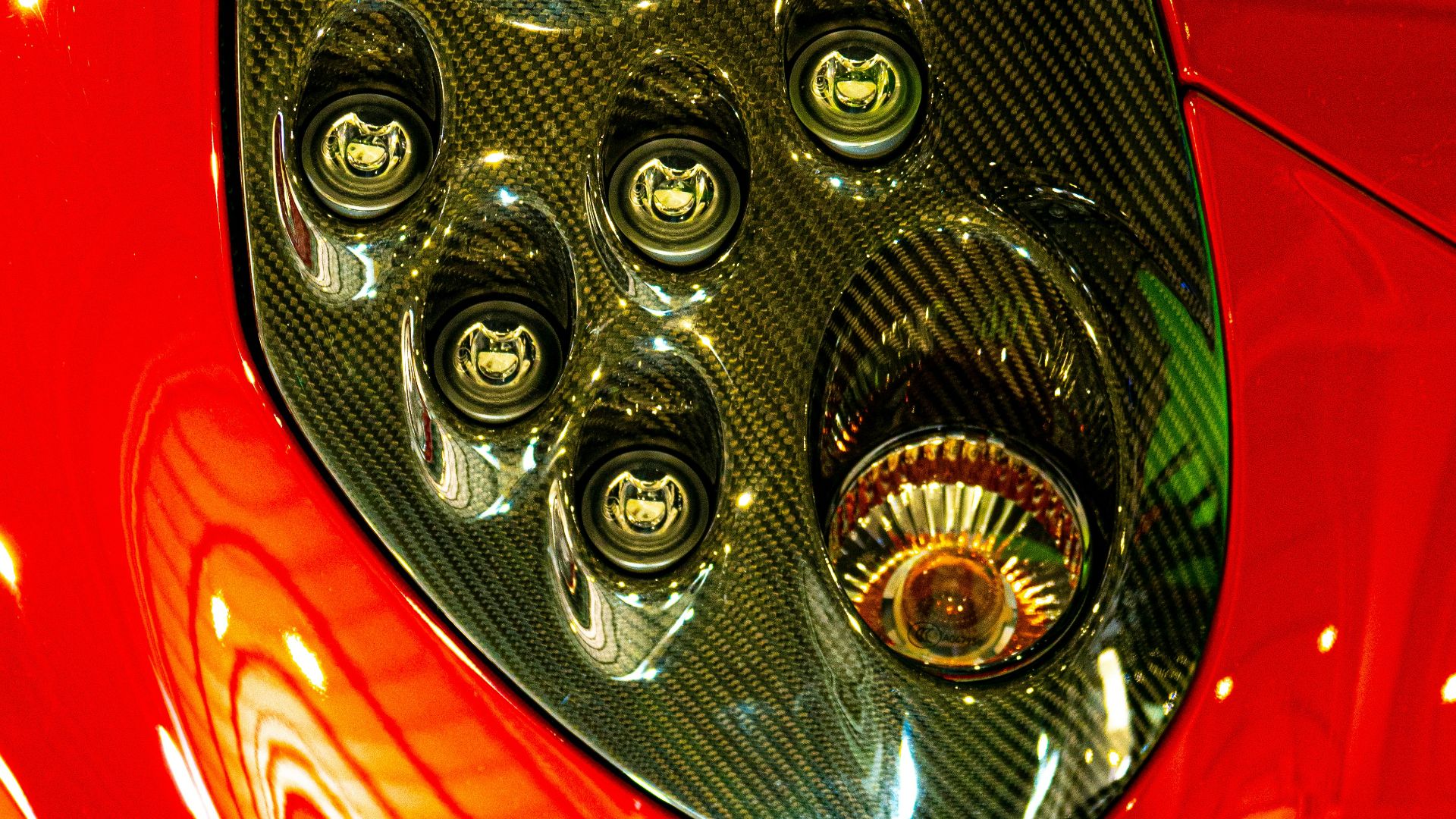 A close-up of a sleek, red car headlight.