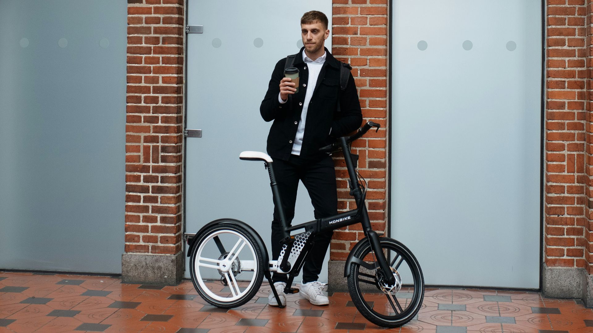 a man standing next to a bike in front of a building