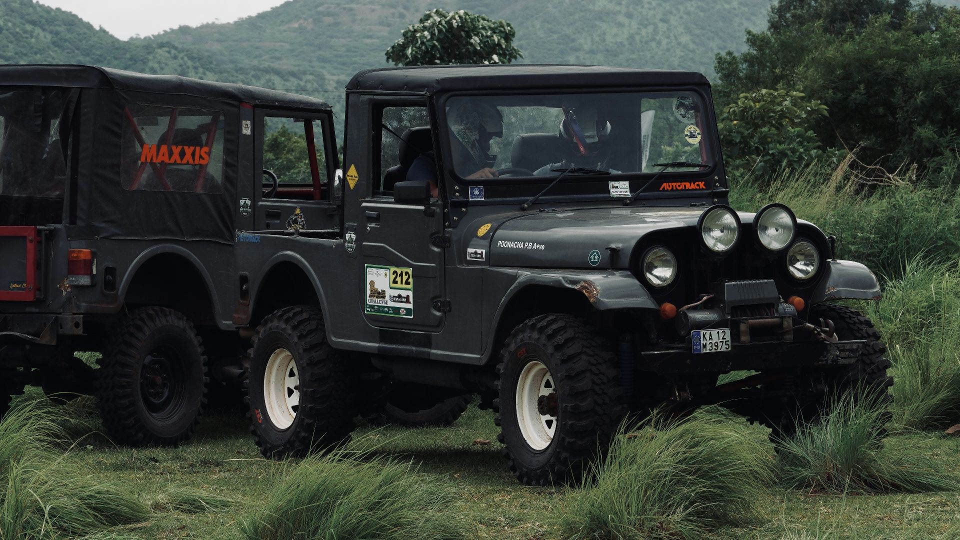 two jeeps are parked in a grassy field