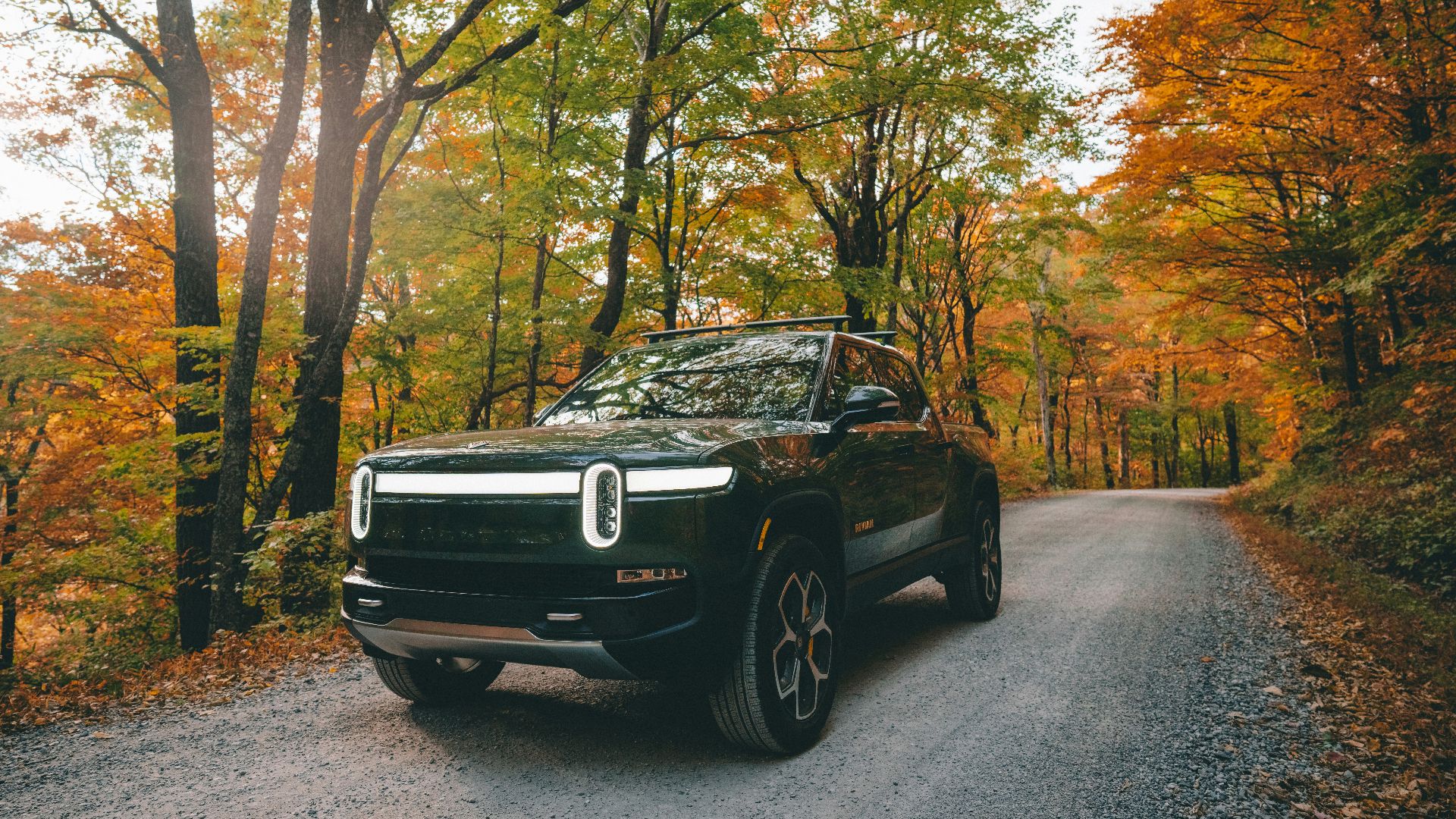 a black car parked on a road surrounded by trees