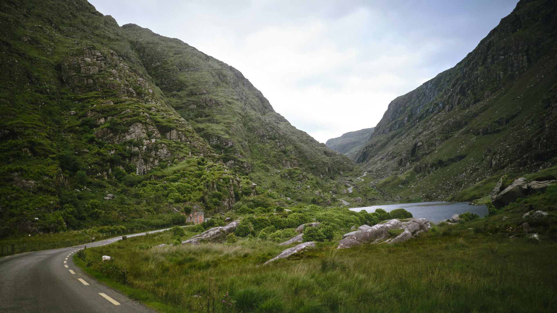 a winding road in the mountains with a lake in the middle