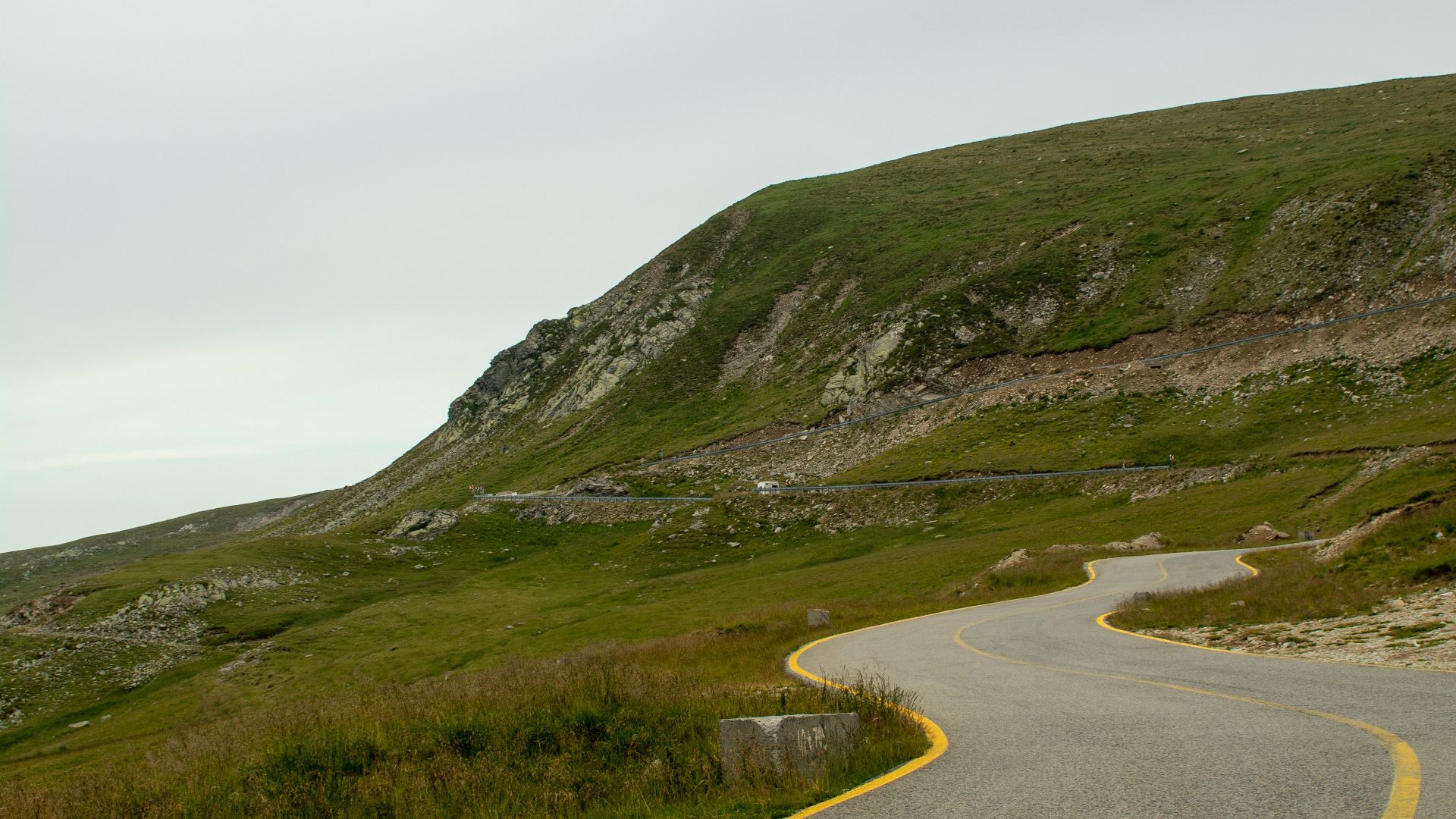 A winding road leads up a green hill.