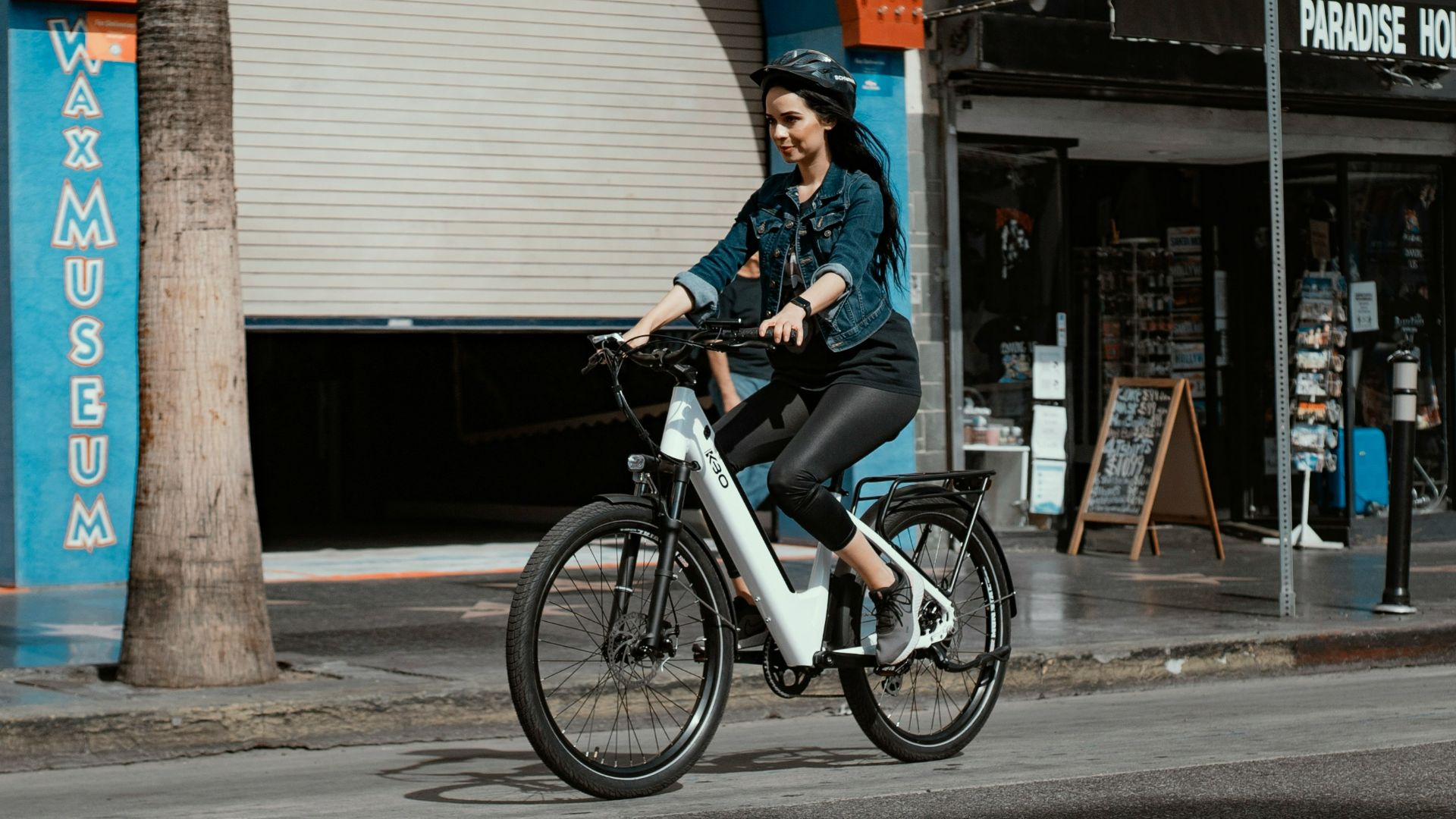 woman in blue denim jacket riding on black bicycle during daytime