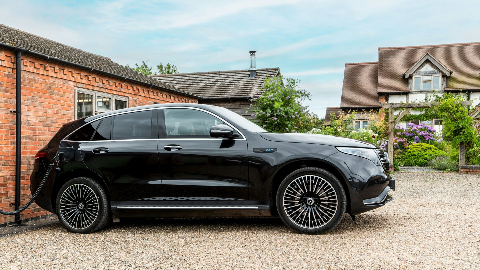 Black electric car charging next to brick building