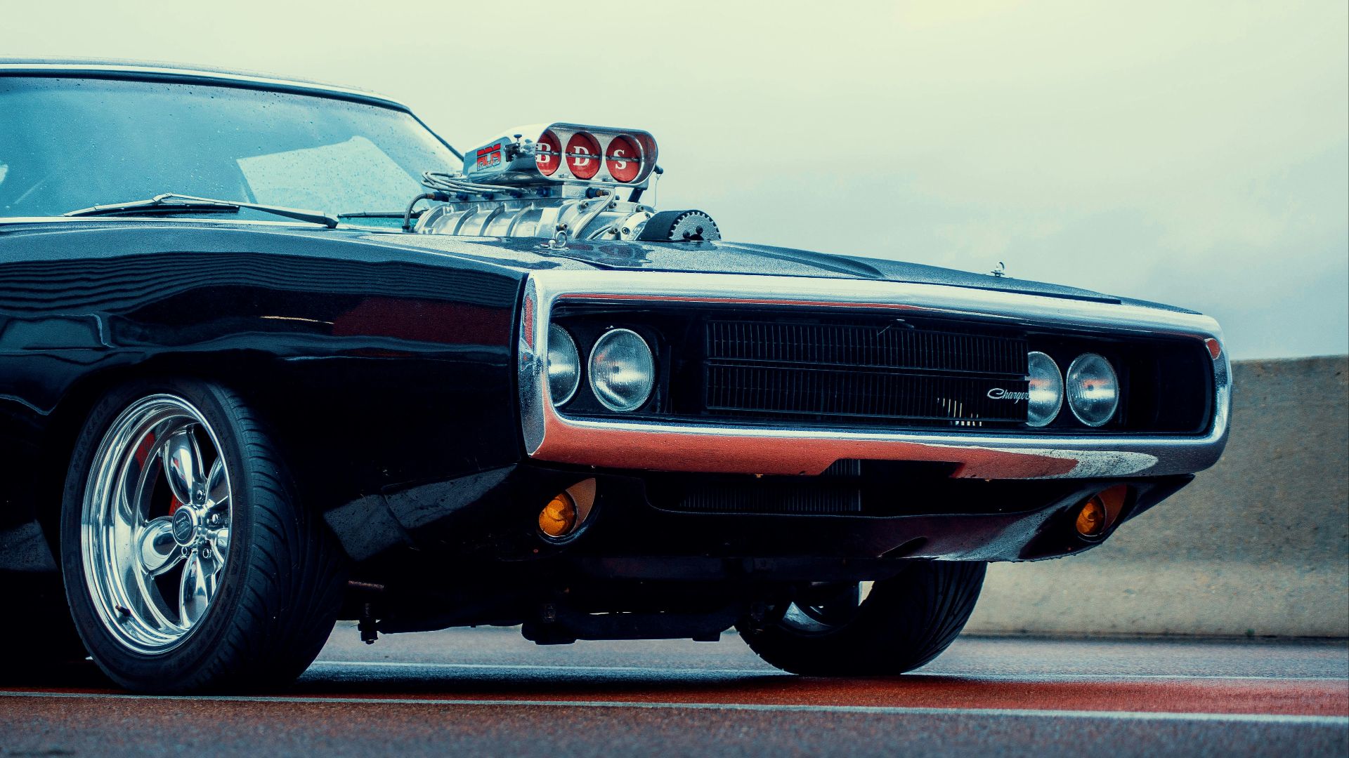 a black muscle car with chrome rims parked on the street