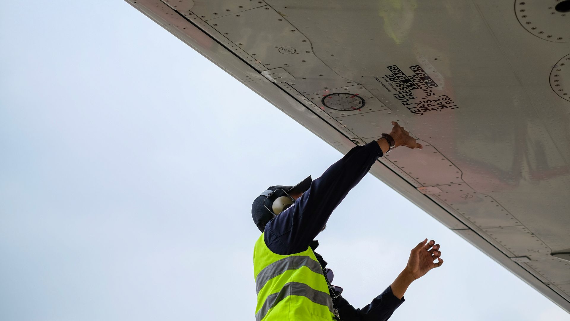 man in green safety vest standing under white structure