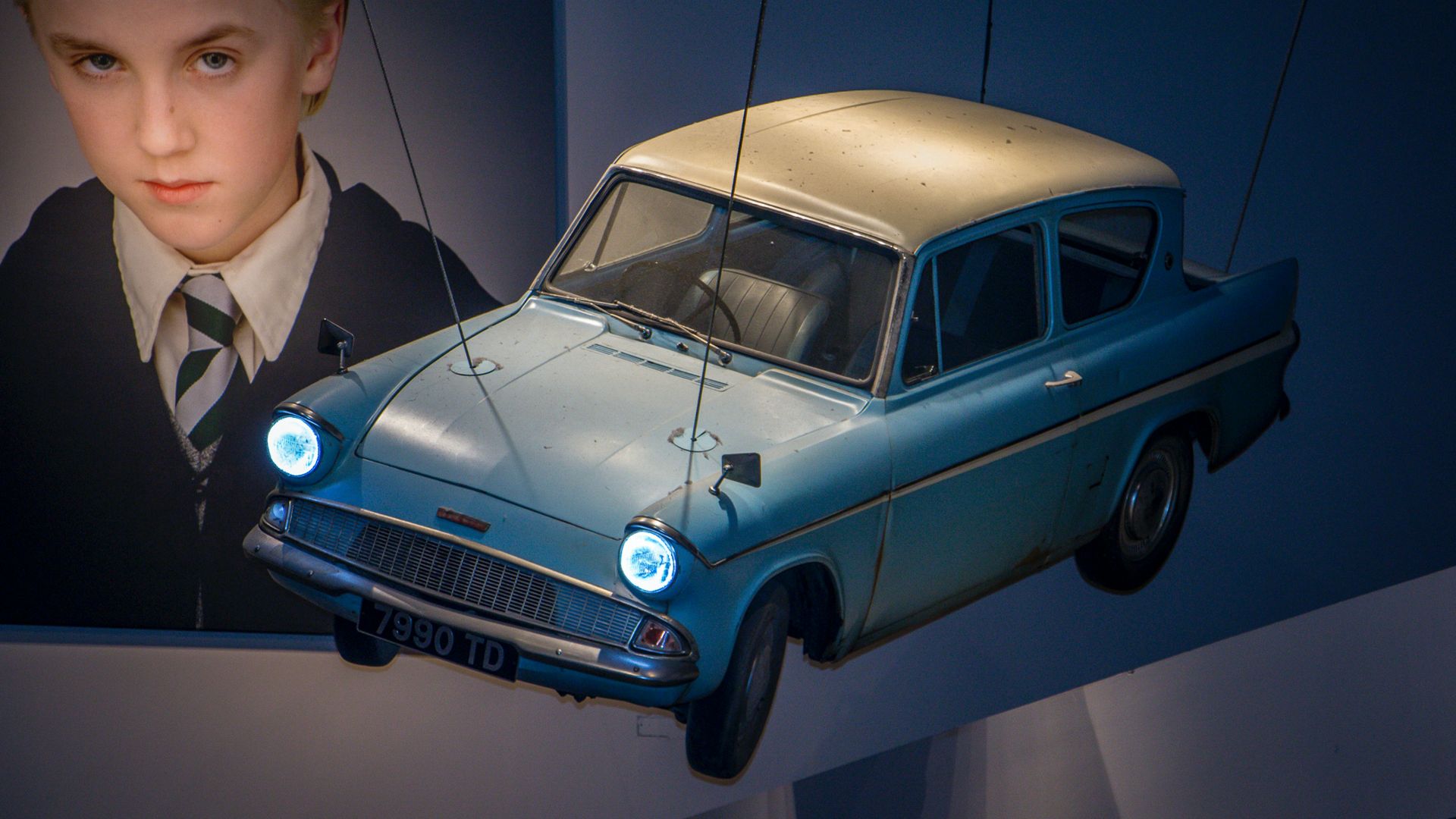 man in black suit jacket standing beside blue car