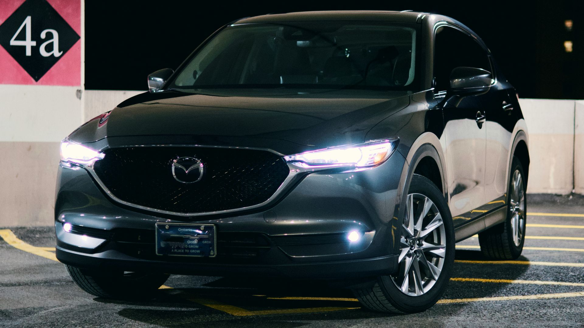 A black mazda suv is parked at night.