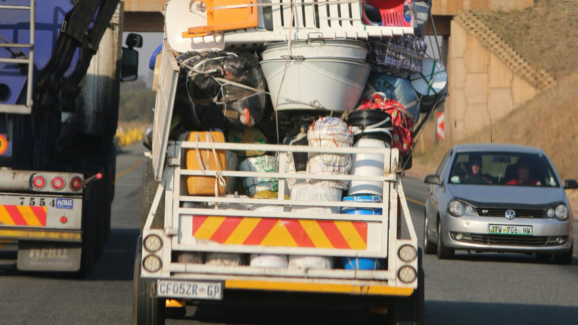 truck carrying plasticware on the road near vehicles during day