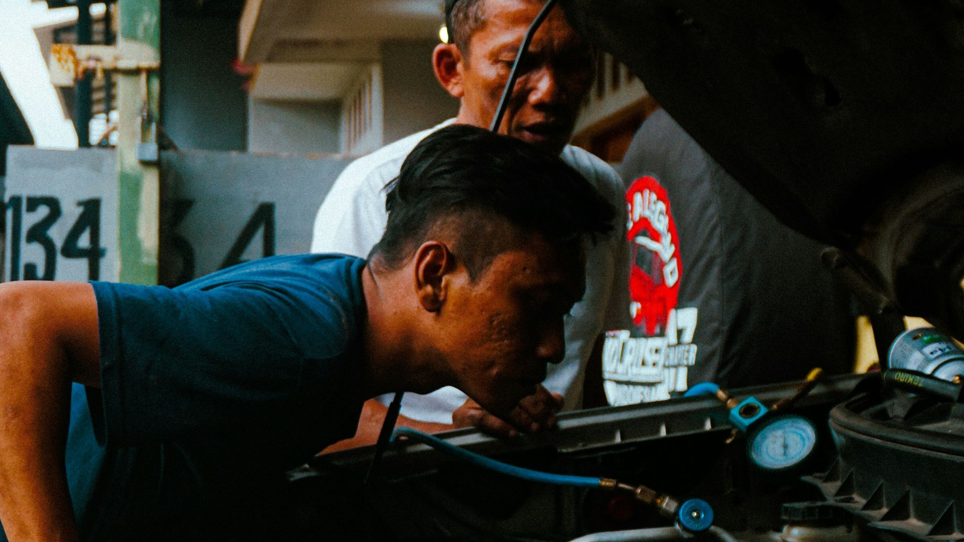 two men working on a car engine in a garage