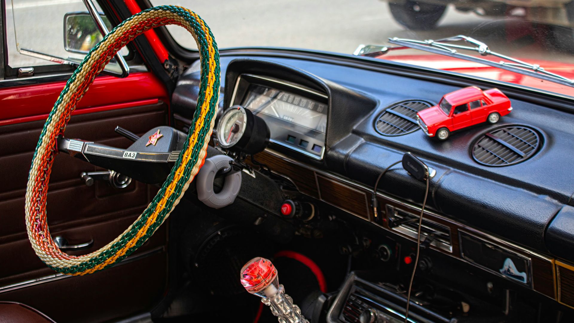 Red toy car on a vintage car dashboard