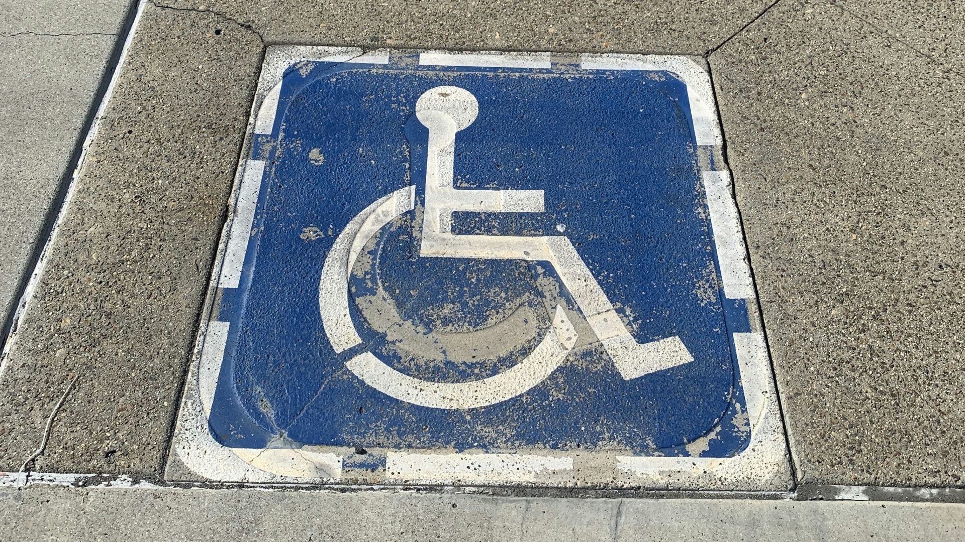 a handicap sign on the sidewalk of a city street