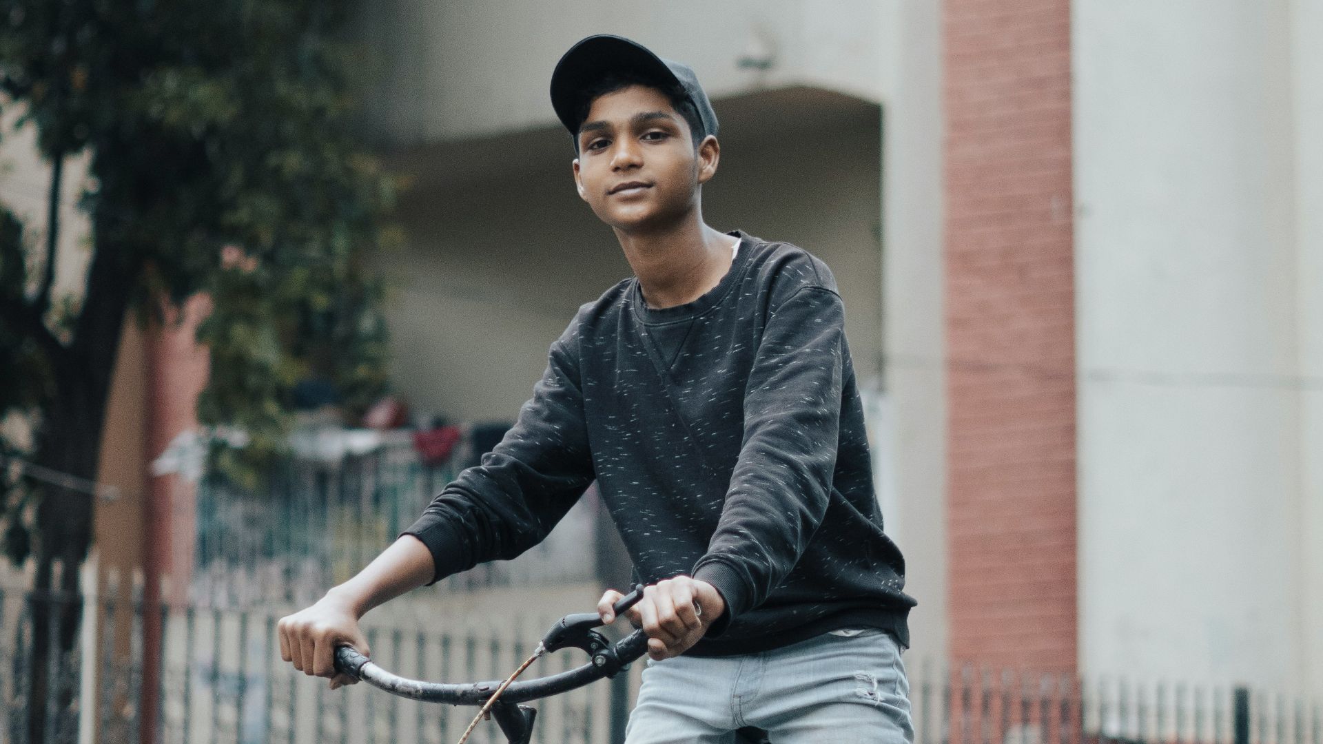 a man riding a bike down a street next to a tall building