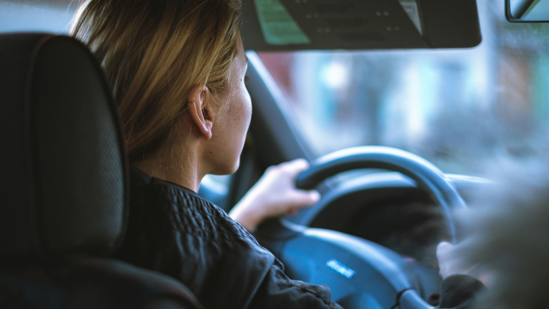 a woman sitting in a car with a steering wheel