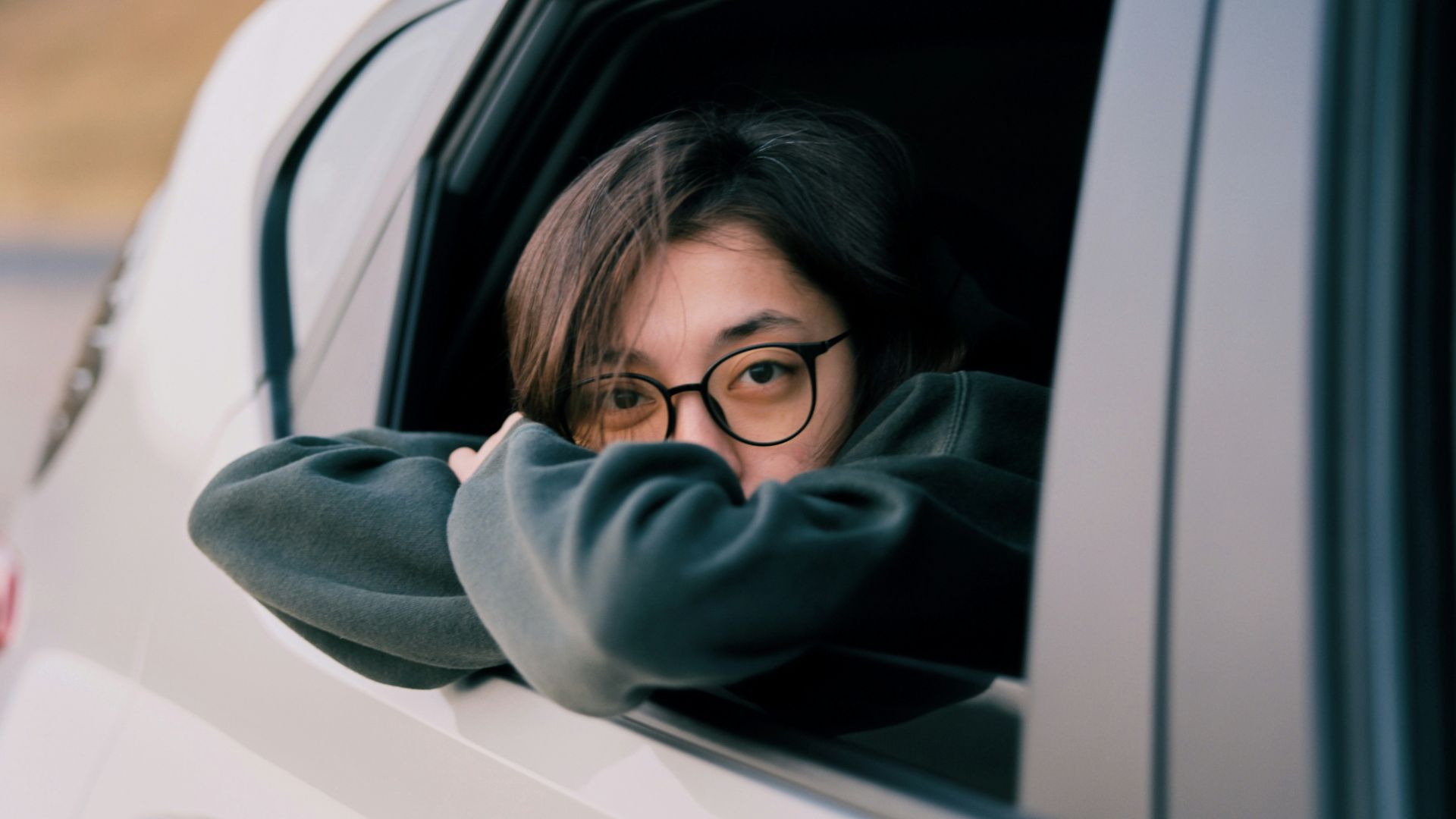 Young woman with glasses looking out car window