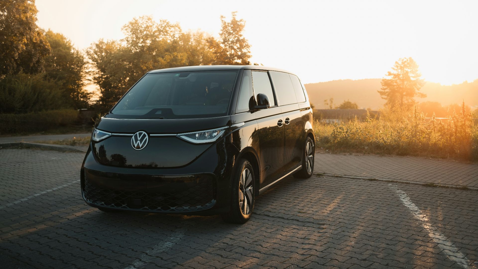 A black van driving down a road next to a forest