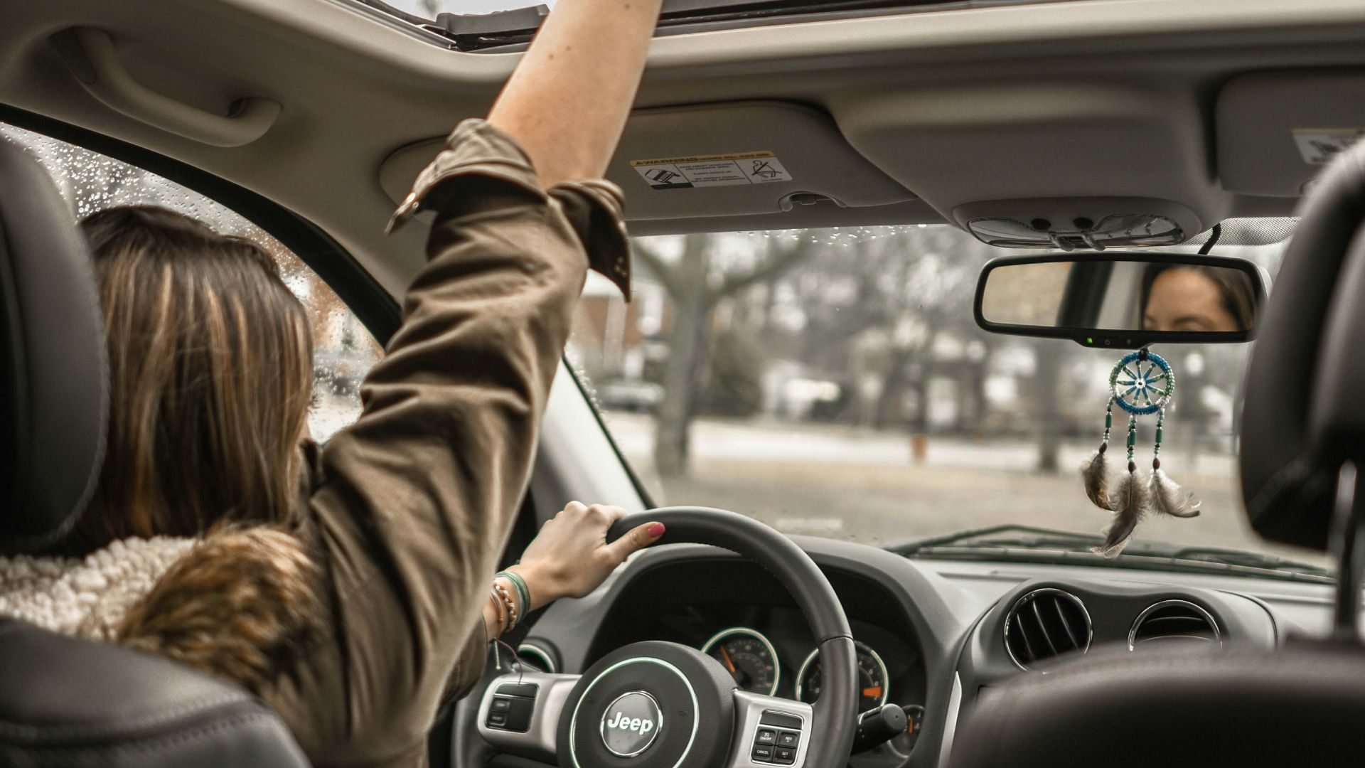 woman raising her right hand inside black and brown vehicle