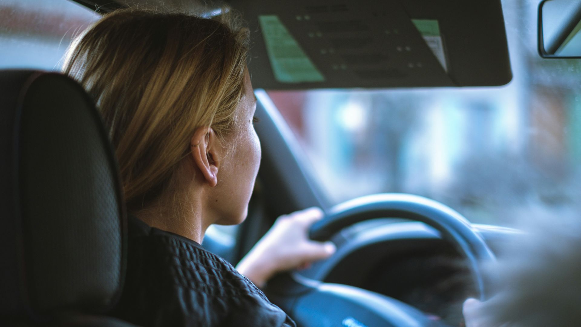 a woman sitting in a car with a steering wheel