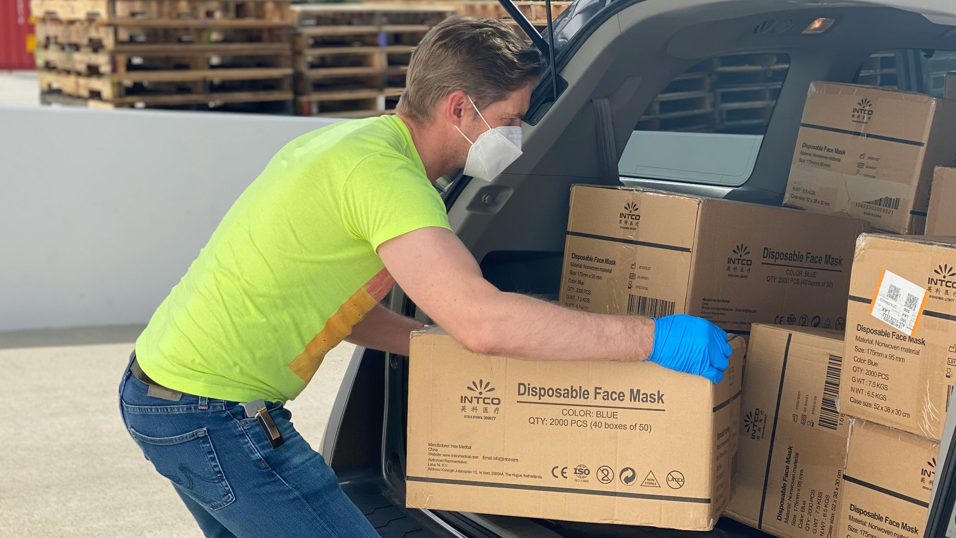 man in green t-shirt and blue denim jeans holding brown cardboard box