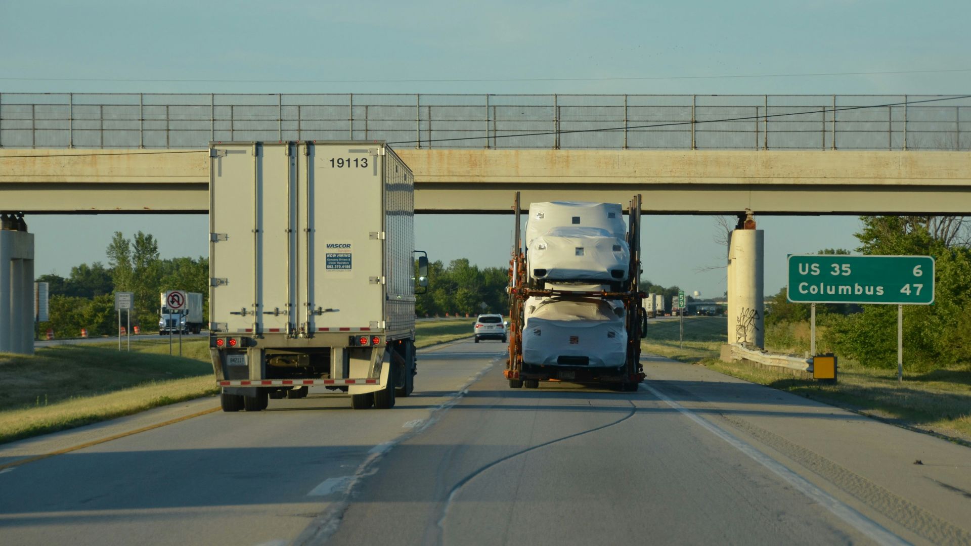 A couple of trucks driving down a highway under a bridge