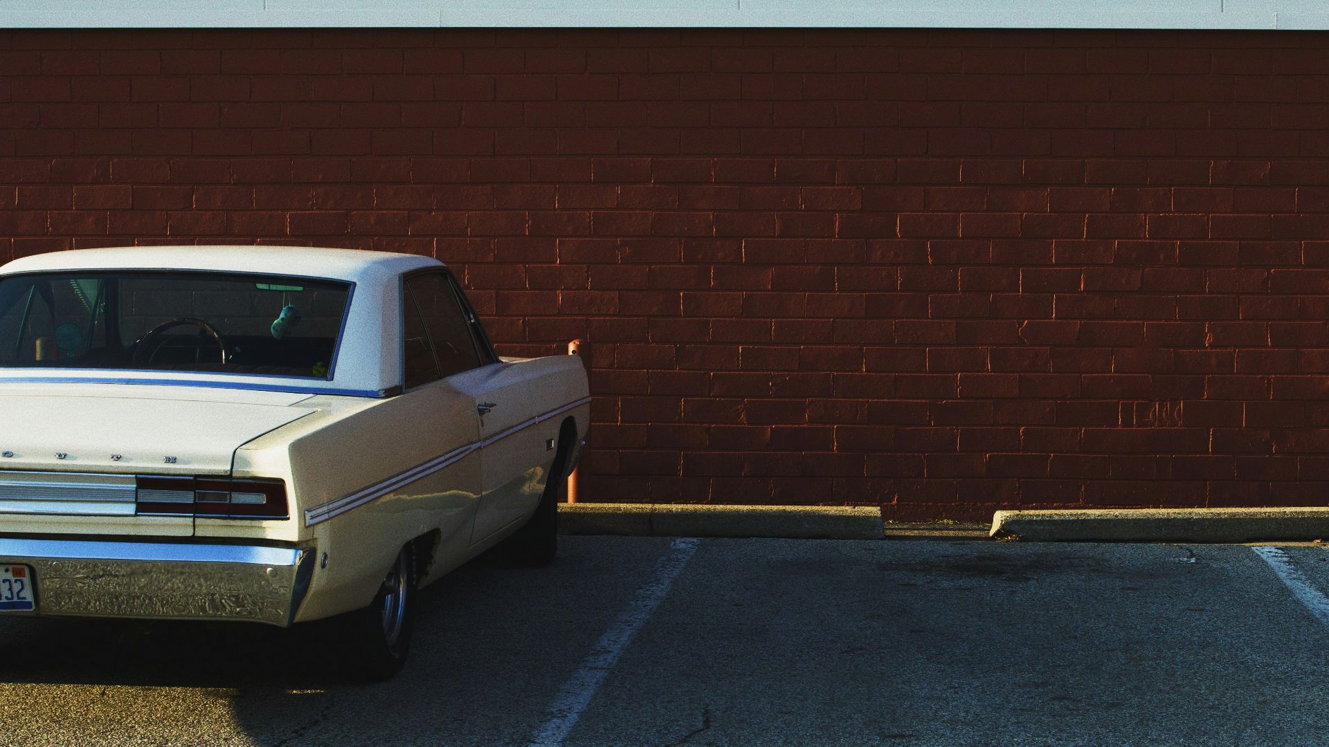 white car parked on parking lot near brown and white wall