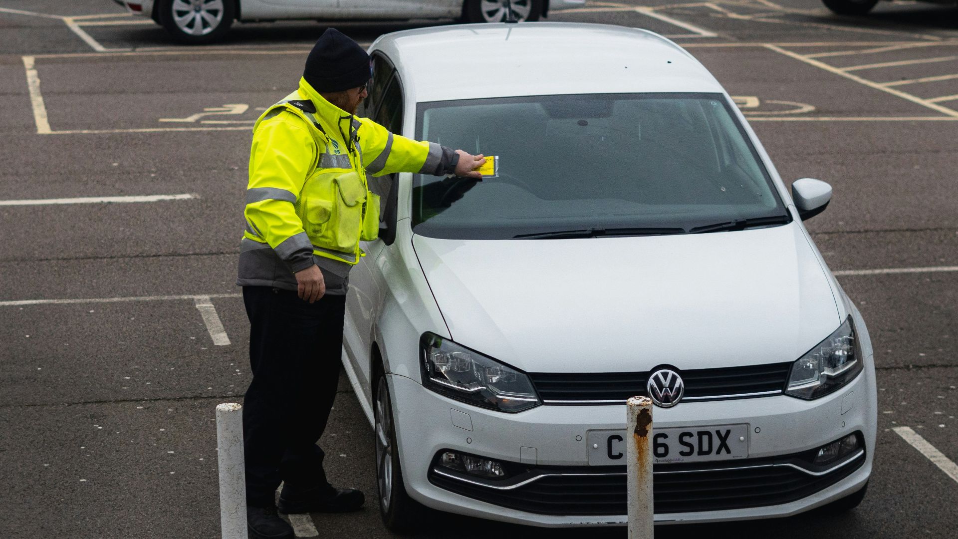 man in yellow jacket standing beside white car